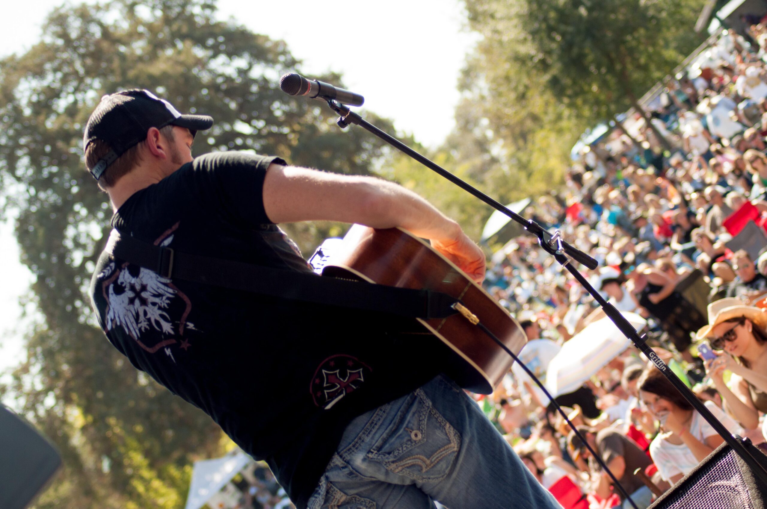 A Person Playing a Guitar With a Microphone in Front of a Crowd